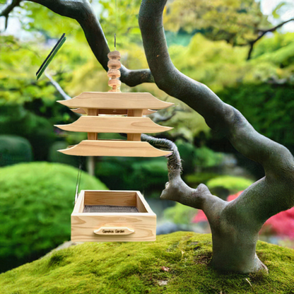 Wooden pagoda-like bird feeder on a mossy rock with a blurred green garden background