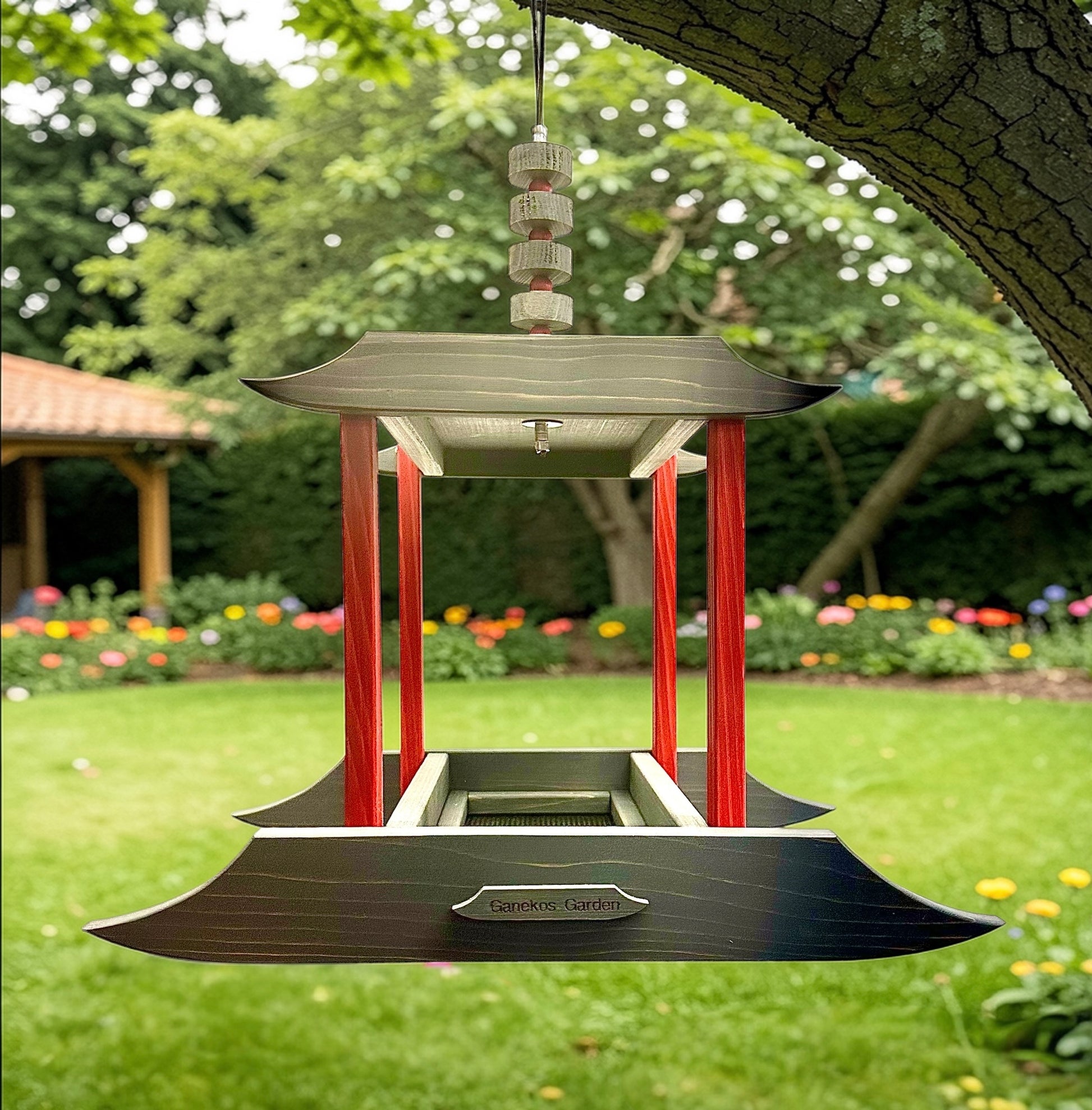 Asian garden bird feeder in a garden setting with trees and flowers in the background.