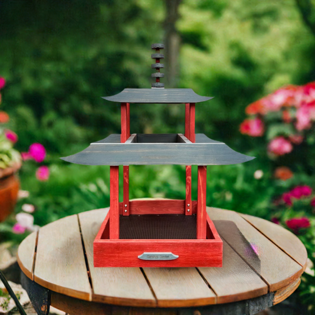 Two-tiered wooden bird feeder on a wooden surface with a garden background